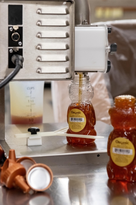 honey containers being filled by machine