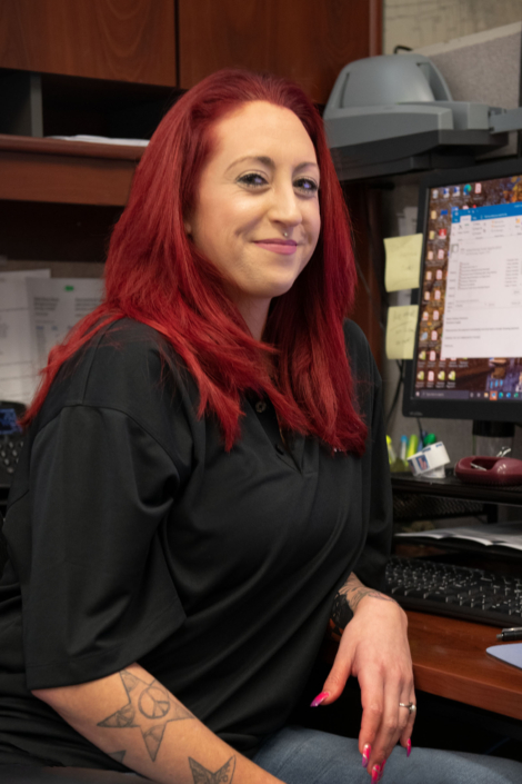 red-haired woman smiling at desk